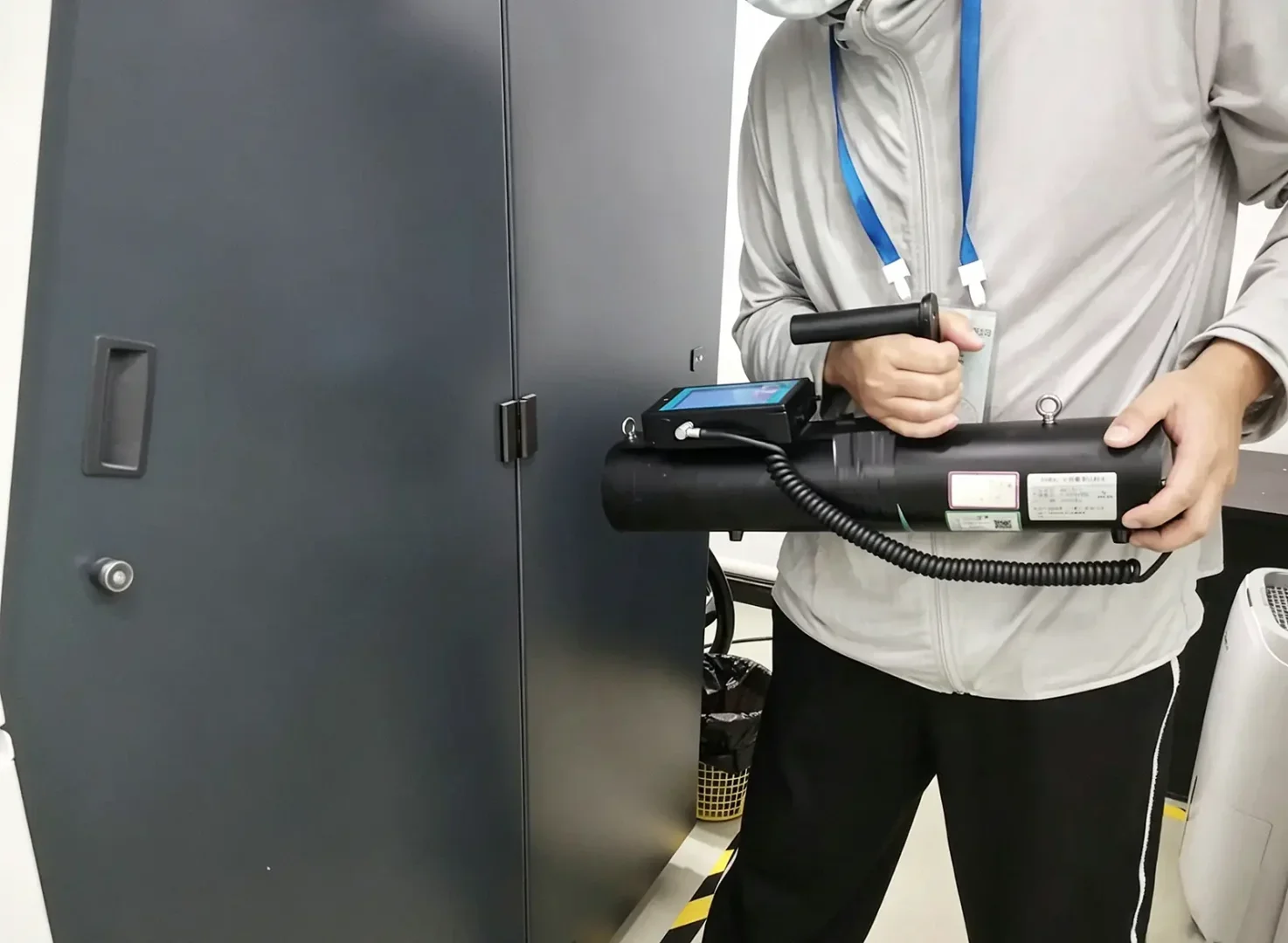 Technician conducting radiation leakage safety test on industrial X-ray CT shielding housing