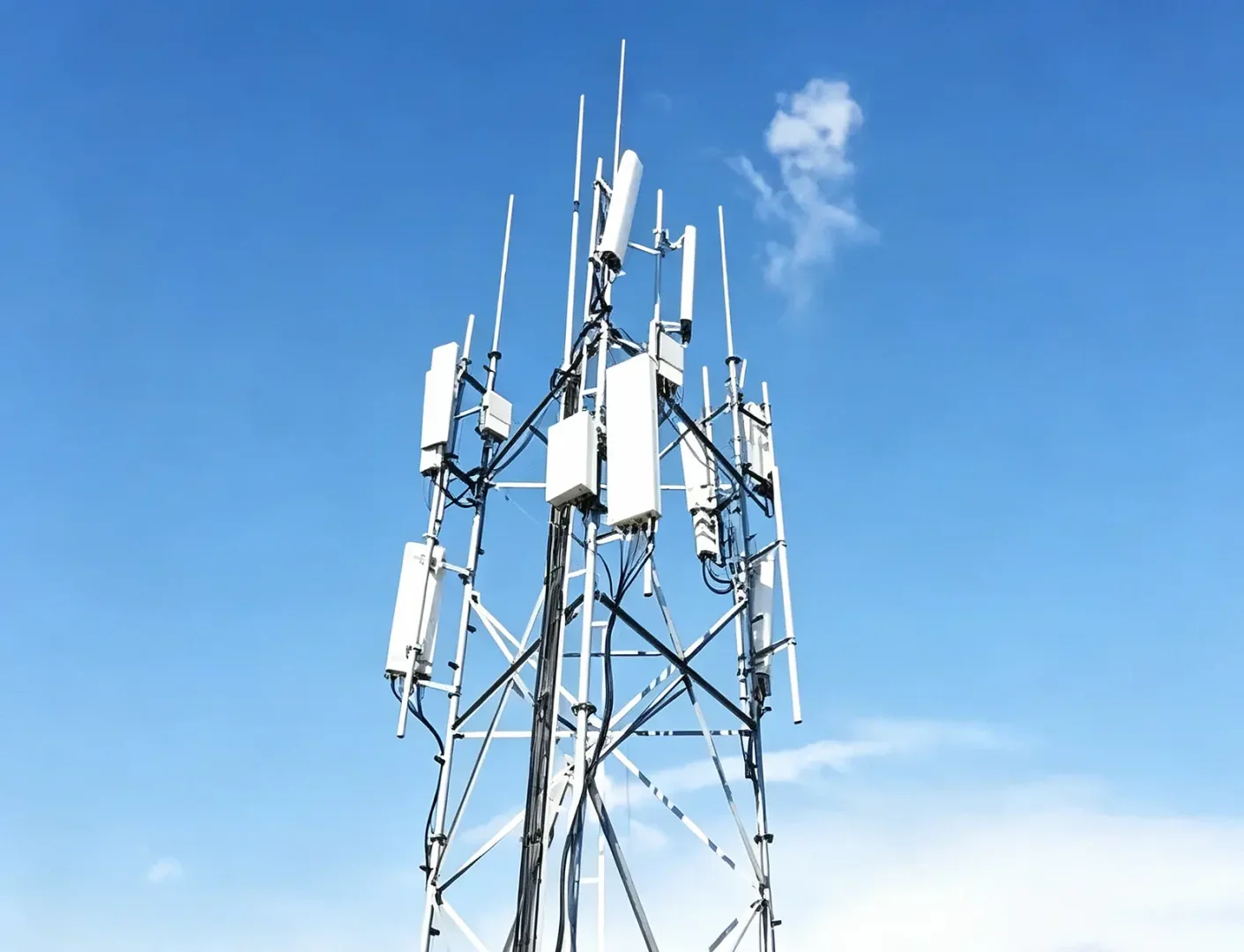 Telecommunication cell tower equipped with backup power energy storage cabinets against clear blue sky