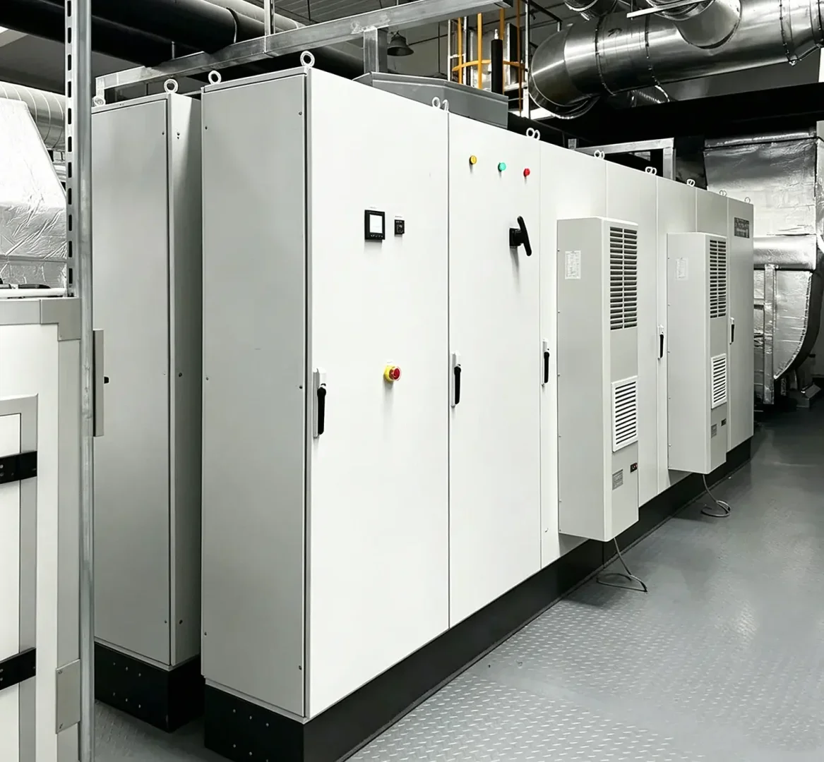 Row of large metal electrical control cabinets installed inside industrial manufacturing facility for automated production systems
