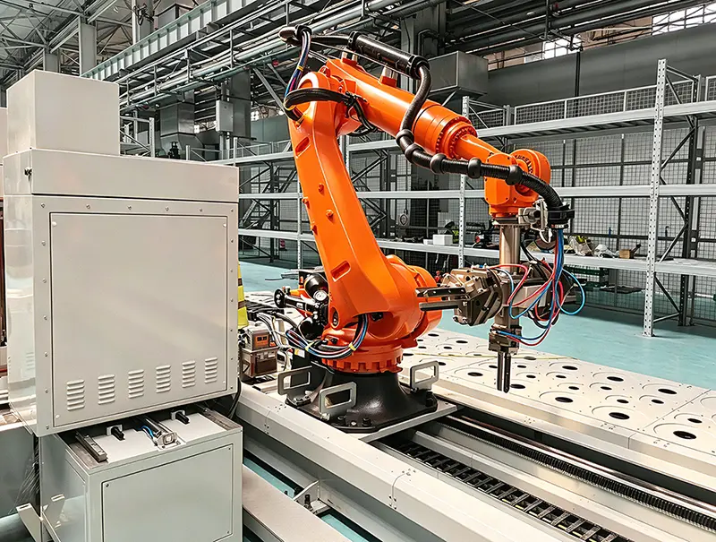 Floor-mounted electrical control cabinet paired with industrial robotic arm inside automated manufacturing workshop